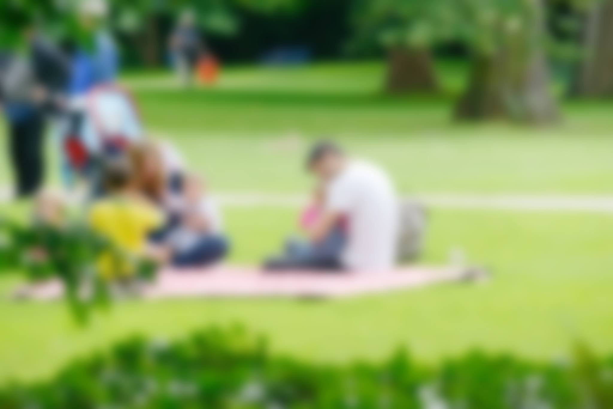 Blurred image of young family with children in summer park.
